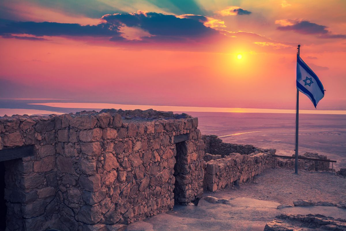 Sunrise over the ruins of Herod’s fortress at Masada, with an Israeli flag on the summit